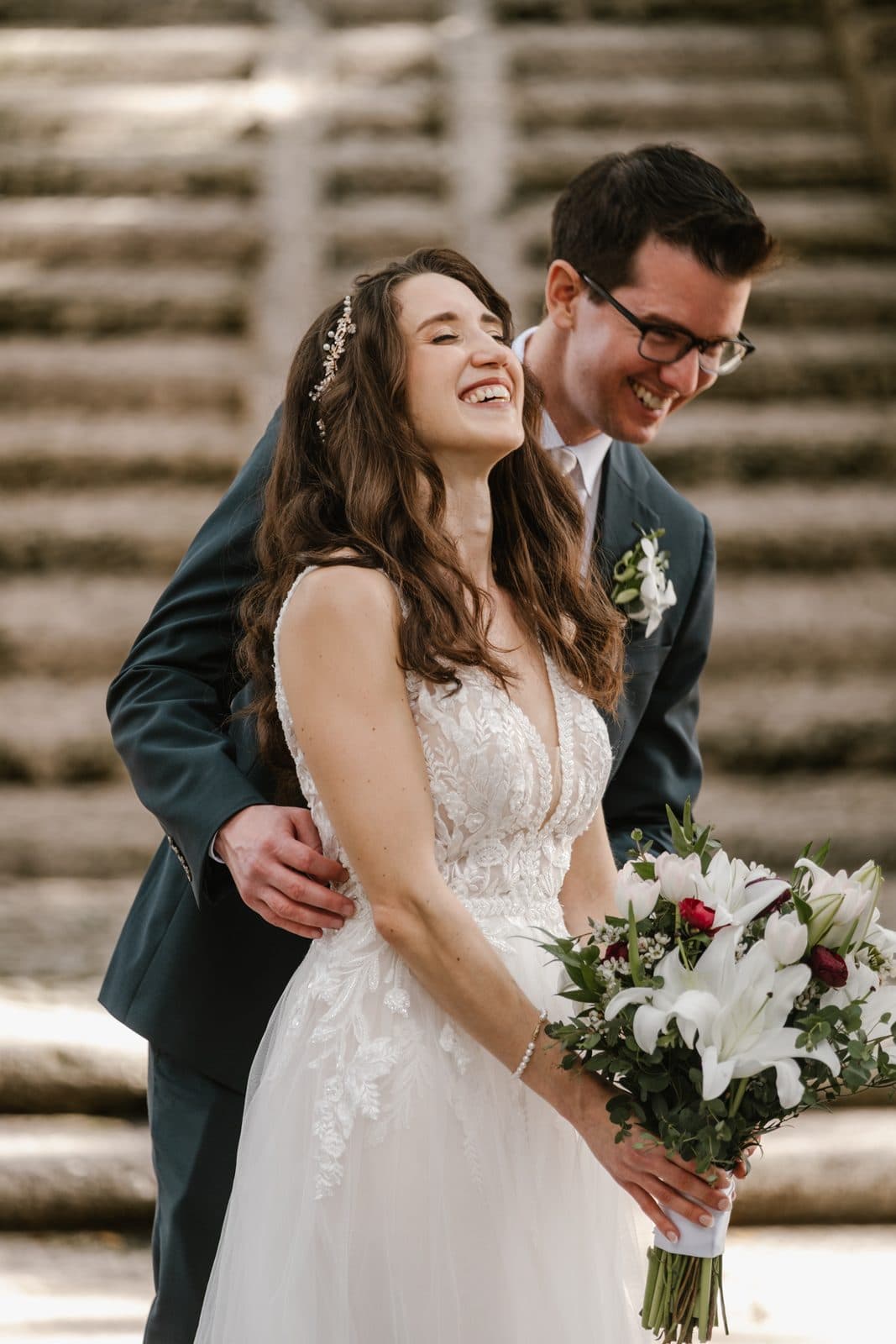 Chloe and Michael laughing together in the stone arches at Vizcaya, Chloe holding a white bouquet